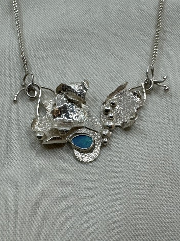 A silver necklace with blue stoneDescription automatically generated